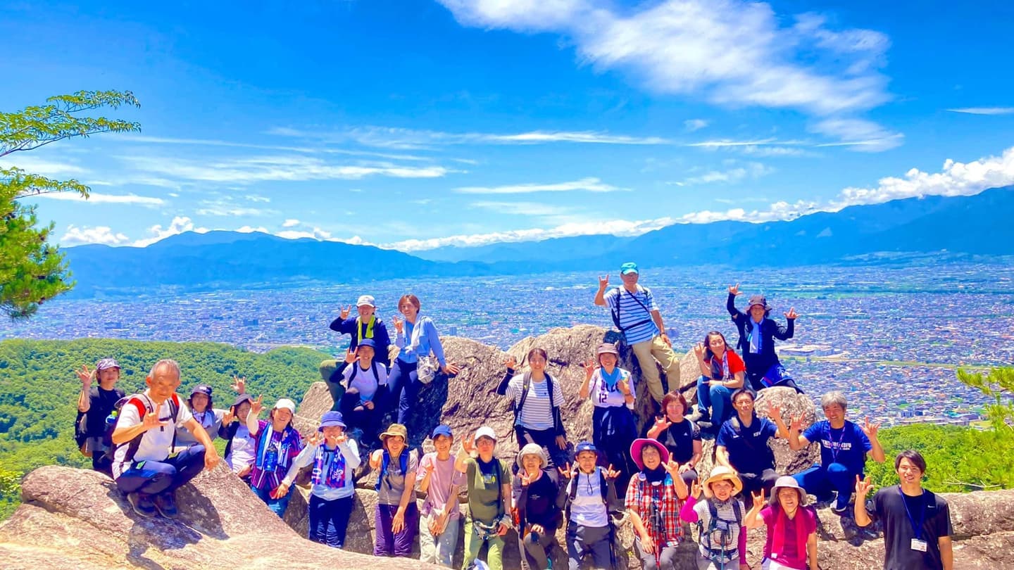 山頂で記念撮影をするグループと絶景の景色